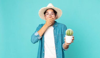 Şok olmuş ve elinde kaktüsle ağzını kapatan genç İspanyol bir adam.