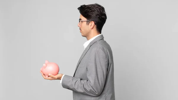 Young Hispanic Man Profile View Thinking Imagining Daydreaming Holding Piggy — Stock Photo, Image