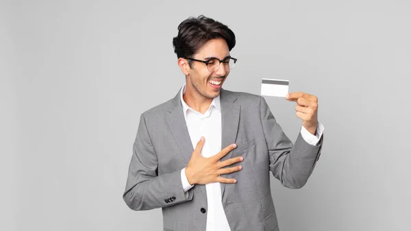 陽気な冗談で大声で笑ってクレジットカードを持っている若いヒスパニック系の男 — ストック写真