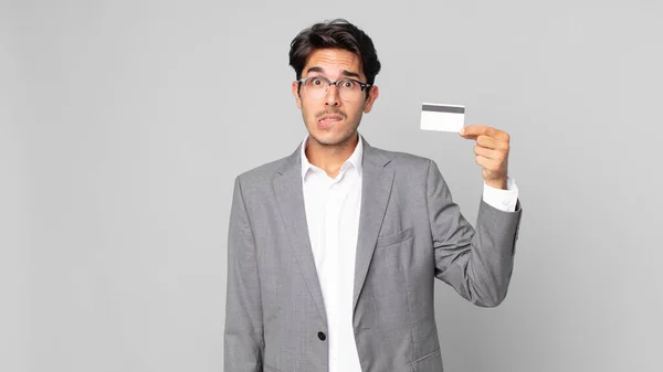 Young Hispanic Man Looking Puzzled Confused Holding Credit Card — Stock Photo, Image