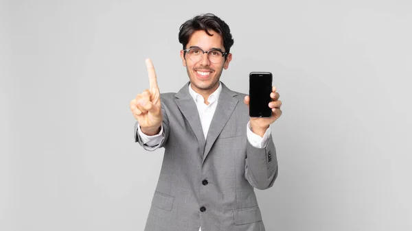 Jovem Hispânico Homem Sorrindo Orgulhosamente Confiantemente Fazendo Número Segurando Smartphone — Fotografia de Stock