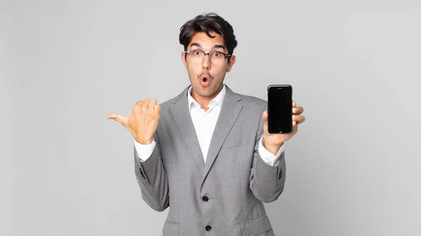 Young Hispanic Man Looking Astonished Disbelief Holding Smartphone — Stock Photo, Image