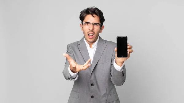 Joven Hombre Hispano Mirando Enojado Molesto Frustrado Sosteniendo Teléfono Inteligente — Foto de Stock