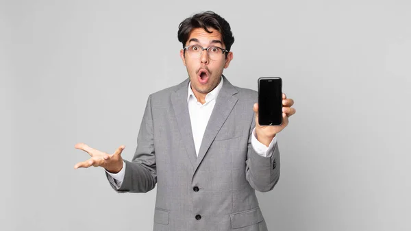 Young Hispanic Man Amazed Shocked Astonished Unbelievable Surprise Holding Smartphone — Stock Photo, Image