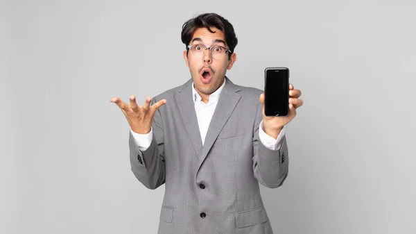 Young Hispanic Man Feeling Extremely Shocked Surprised Holding Smartphone — Stock Photo, Image