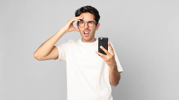 Nuori Latino Mies Näyttää Onnellinen Hämmästynyt Yllättynyt Tilalla Älypuhelin — kuvapankkivalokuva