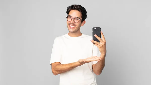 Joven Hispano Sonriendo Alegremente Sintiéndose Feliz Mostrando Concepto Sosteniendo Smartphone —  Fotos de Stock