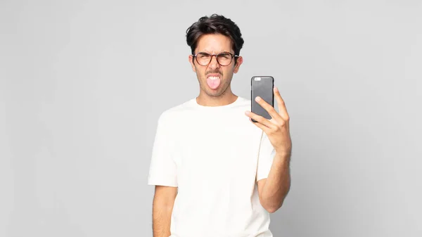 Jeune Homme Hispanique Sentant Dégoûté Irrité Langue Dehors Tenant Smartphone — Photo