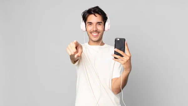 Nuori Latino Mies Osoittaa Kameraan Valitsemalla Sinut Kuulokkeet Älypuhelin — kuvapankkivalokuva