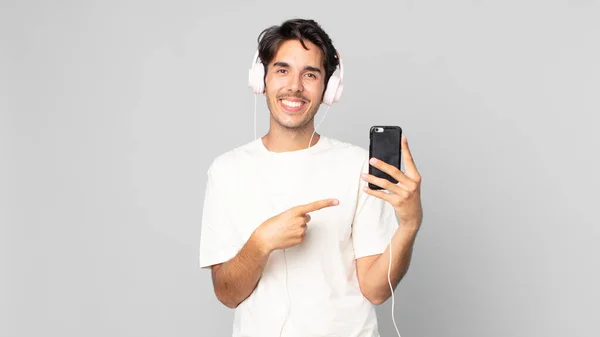 Joven Hispano Sonriendo Alegremente Sintiéndose Feliz Señalando Lado Con Auriculares — Foto de Stock