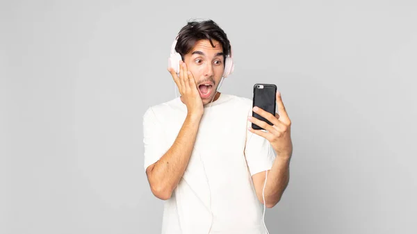 Nuori Latino Mies Tunne Onnellinen Innoissaan Yllättynyt Kuulokkeet Älypuhelin — kuvapankkivalokuva