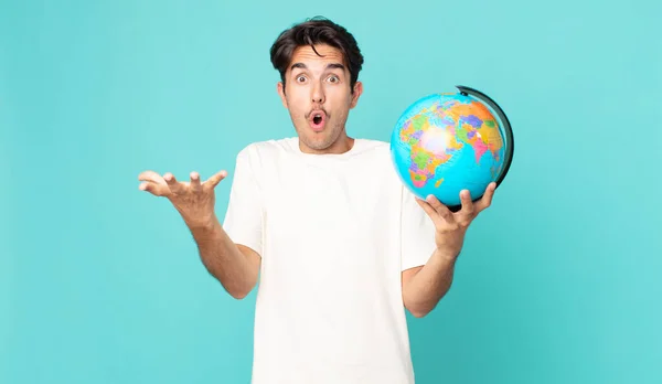 Young Hispanic Man Feeling Extremely Shocked Surprised Holding World Globe — Stock Photo, Image