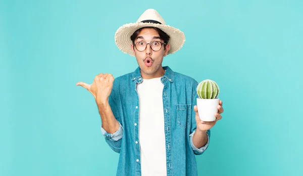 Młody Hiszpan Wyglądający Zdumionego Niedowierzaniem Trzymający Kaktusa — Zdjęcie stockowe
