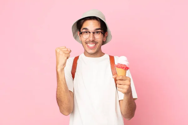 若いヒスパニックな男はショックを受けて笑って成功を祝いアイスクリームを持っています — ストック写真