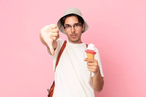 若いヒスパニック系の男が十字架を感じ親指を下げてアイスクリームを持っています — ストック写真