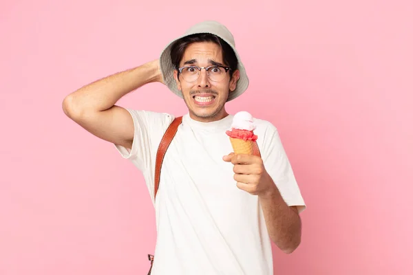 若いヒスパニック系の男はストレスや不安や恐怖を感じ頭に手を置きアイスクリームを持っています — ストック写真