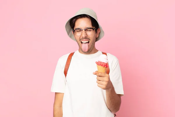 陽気で反抗的な態度の若いヒスパニック系の男冗談と舌を突き出してアイスクリームを持っている — ストック写真