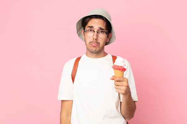 不幸な表情をして泣きながらアイスクリームを抱えている若いヒスパニック系の男が — ストック写真