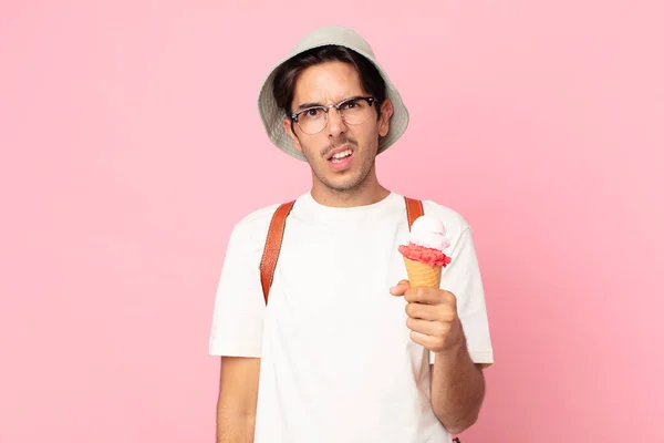 若いヒスパニック系の男は困惑し混乱しアイスクリームを持っています — ストック写真
