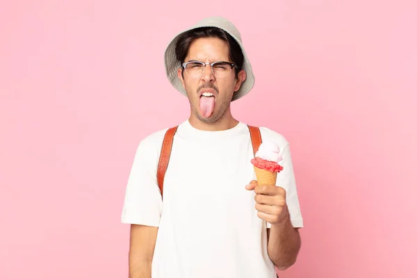 若いヒスパニック系の男はうんざりしていらいらして舌を出してアイスクリームを持っています — ストック写真