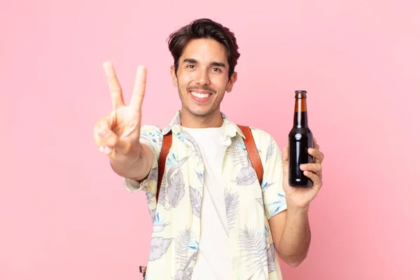 若いヒスパニック系の男は笑顔と幸せそうな顔勝利や平和をジェスチャーやビールのボトルを保持 — ストック写真
