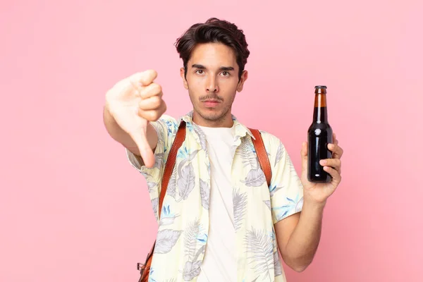 若いヒスパニック系の男が十字架を感じ親指を立ててビールを持っています — ストック写真