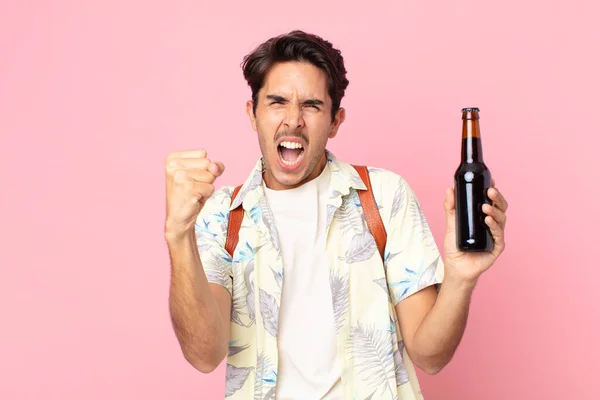 Młody Hiszpan Krzyczący Agresywnie Gniewnym Wyrazem Twarzy Trzymający Butelkę Piwa — Zdjęcie stockowe