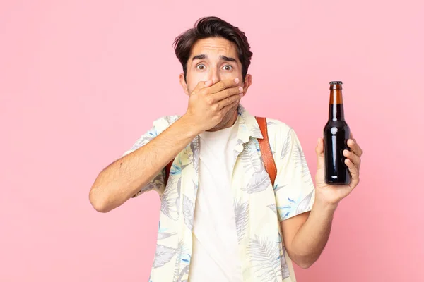 Młody Hiszpan Zakrywający Usta Dłońmi Wstrząśniętymi Trzymający Butelkę Piwa — Zdjęcie stockowe