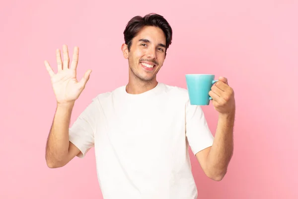 若いヒスパニック系の男が手を振ってあなたを歓迎し挨拶しコーヒーマグカップを持って — ストック写真
