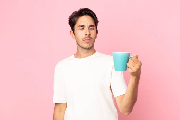 若いヒスパニック系の男は悲しい気持ち 動揺や怒りと側面を見て コーヒーマグカップを保持 — ストック写真