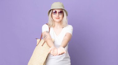 Genç ve güzel albino kadın mutlu bir şekilde gülümsüyor ve bir konsept sunuyor. yaz konsepti
