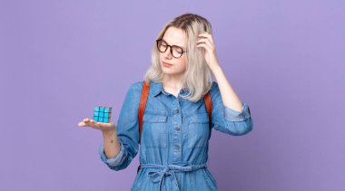 Genç, güzel albino kadın kafası karışmış ve kafası karışmış hissediyor, kafasını kaşıyor ve bir zeka oyunu çözüyor.