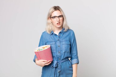 Genç, güzel albino kadın kafası karışmış ve patlamış mısırla kafası karışmış.