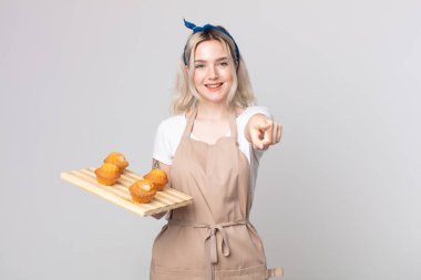 Genç ve güzel albino kadın kamerayı işaret ederek seni kek tepsisiyle seçiyor.