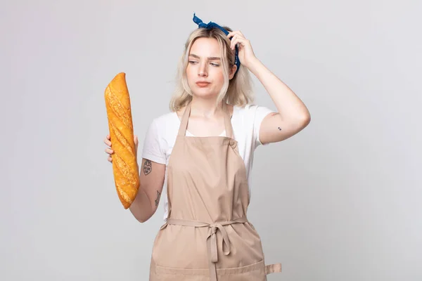 年轻漂亮的白化病妇女感到困惑和困惑 用面包面包面包抓挠着头 — 图库照片