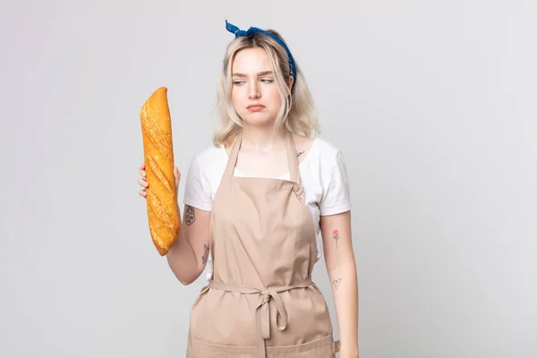 年轻漂亮的白化病妇女感到悲伤 不安或愤怒 一边看着旁边的面包面包面包 — 图库照片