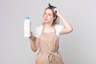 Genç, güzel albino kadın şaşkın ve kafası karışmış hissediyor. Kafasını bir şişe sütle kaşıyor.