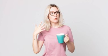 Genç, güzel albino kadın stresli, endişeli, yorgun ve bir kahve fincanıyla hayal kırıklığına uğramış hissediyor.