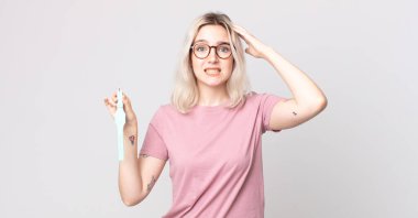 Genç, güzel albino kadın kendini stresli, endişeli ya da korkmuş hissediyor. Elleri başında bir saat tutuyor.