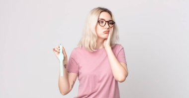 Genç, güzel albino kadın, saati tutan yorgun ve uykulu bir kadından sıkılmış ve hayal kırıklığına uğramış hissediyor.