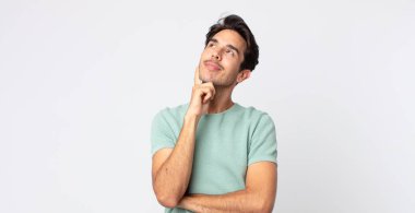 İspanyol yakışıklı adam mutlu bir şekilde gülümsüyor ve hayal kuruyor ya da şüphe ediyor, yana bakıyor.