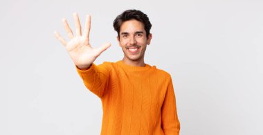 İspanyol yakışıklı adam gülümsüyor ve arkadaş canlısı görünüyor, 5 ya da 5 numarayı gösteriyor, elleri önde, geri sayıyor.