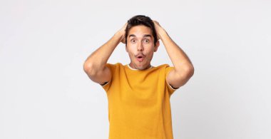 İspanyol yakışıklı adam heyecanlı ve şaşırmış görünüyor, ağzı açık, iki eli başında, kendini şanslı hissediyor.