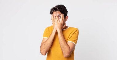 İspanyol yakışıklı adam korkmuş ya da utanmış hissediyor, gözleri yarı kapalı ya da elleri kapalı gözetliyor.