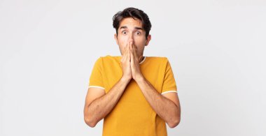 Hispanik yakışıklı adam endişeli, üzgün ve korkmuş hissediyor, elleriyle ağzını kapatıyor, endişeli ve berbat görünüyor.