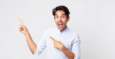 İspanyol yakışıklı adam mutlu ve şaşırmış hissediyor, şok olmuş bir ifadeyle gülümsüyor ve bir tarafı işaret ediyor.