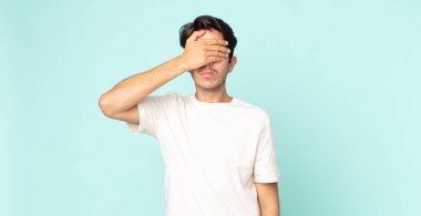 İspanyol yakışıklı bir adam tek eliyle gözlerini kapatıyor korkmuş ya da endişeli hissediyor, merak ediyor ya da körü körüne bir sürpriz bekliyor.