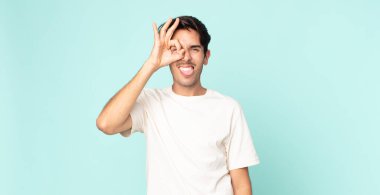 İspanyol yakışıklı adam mutlu bir şekilde gülümsüyor, şaka yapıyor ve gözetleme deliğinden bakıyor, sırları gözetliyor.