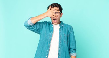 İspanyol yakışıklı adam şok olmuş, korkmuş ya da korkmuş görünüyor. Yüzü elle kaplanmış ve parmaklarının arasından gizlice bakıyor.