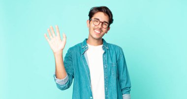 İspanyol yakışıklı adam mutlu ve neşeyle gülümsüyor, el sallıyor, seni selamlıyor ya da veda ediyor.